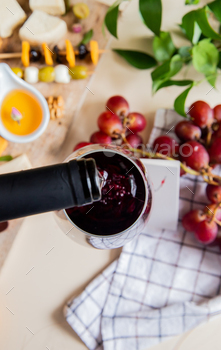 top view of red wine pouring into glass and different kinds of cheese, butter, olive, walnut, grape / Photodune, Misc
