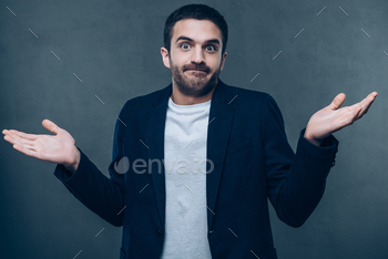 arms and grimacing while standing against grey background