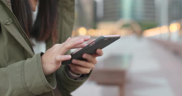 Woman use of smart phone, body part of woman wearing winter jacket in the evening