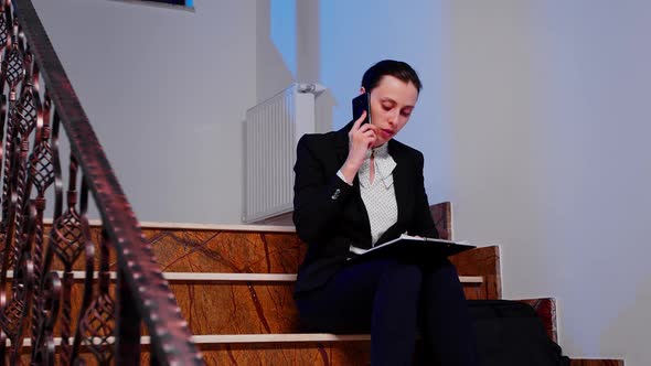 Businesswoman Reading Project During Phone Call