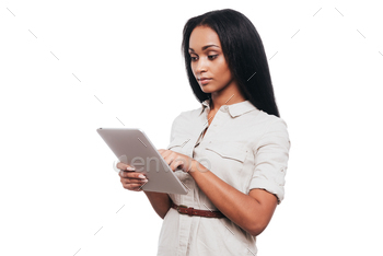 an woman working on digital tablet while standing against white background