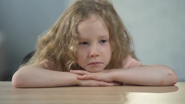 Orphan Girl Sitting at the Table and Thinking About Parents at Boarding School