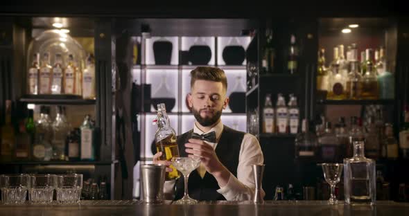 The Bartender Is Pouring Alcohol From a Bottle Into a Shaker Using a Measuring Cup. 