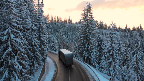Aerial view of winter landscape with snow covered mountain hills and winding forest road