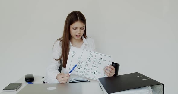 Young Girl Explaining the Images at Camera at Workplace During Remote Working