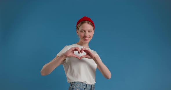 Closeup of Smiling Young Woman Making Sign Heart Shape By Hand Posing