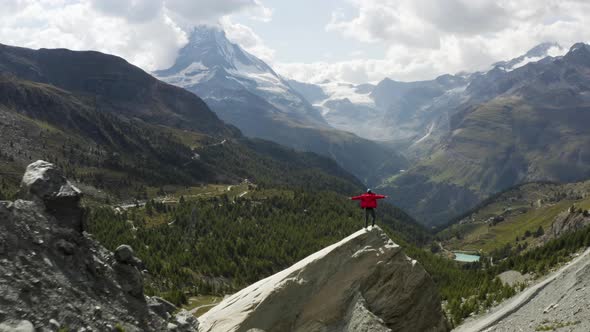 Aerial passes a young hiker with an epic view over the Matterhorn, Zermatt, Switzerland