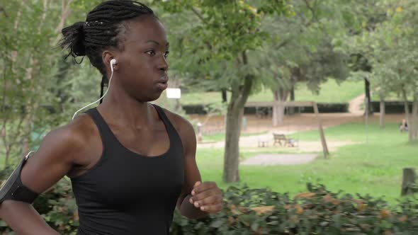 Attractive american african young woman running in the park. Training,strenght