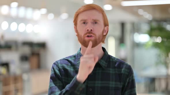 Portrait of Beard Redhead Man with Finger on Lips Quiet Sign