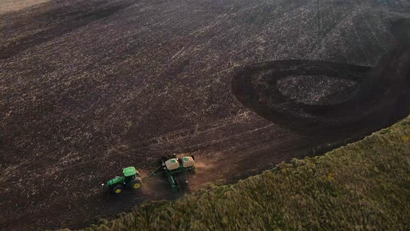 Aerial view, drone view of green tractor with plough working on a field,