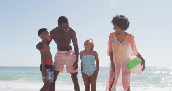 Portrait of smiling african american family embracing on sunny beach