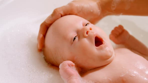 Mother giving her baby boy a bath in bathroom 4k