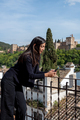 female tourist messaging on mobile phone while standing on terrace with views to Alhambra - PhotoDune Item for Sale