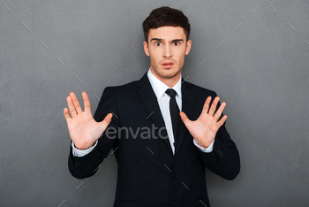 g arms raised and expressing negativity while standing against grey background
