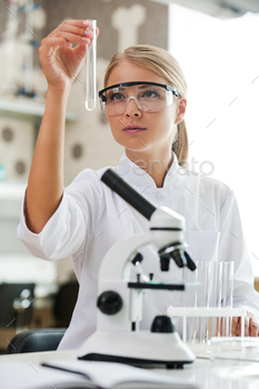 male scientist holding test tube and looking at it while working in the laboratory
