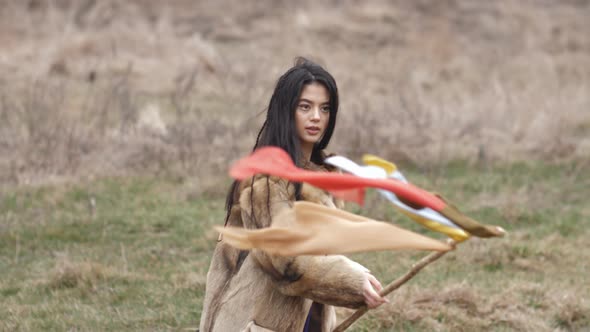 asian young mestizo woman in ethnic clothes posing and waving a bandana flag in the steppe in nature