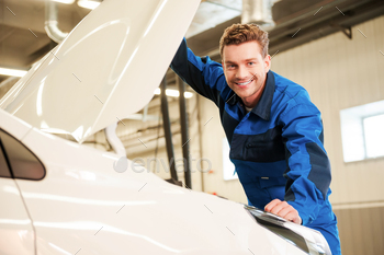 orm examining car and smiling while standing in workshop