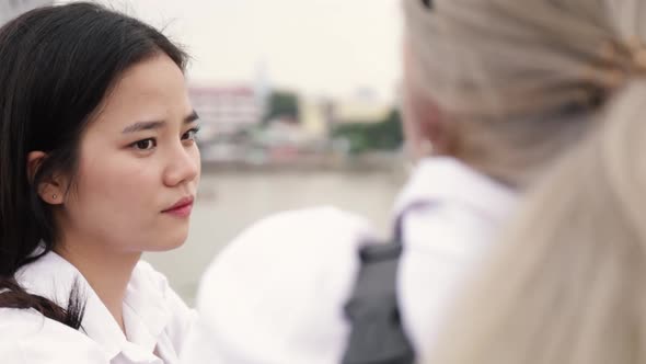 Asian lesbian couple talking while standing on the bridge.