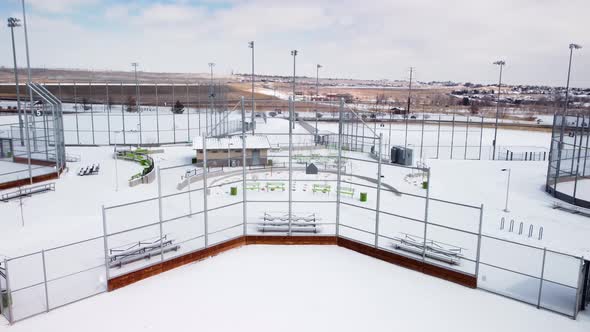 Tilt down of baseball and softball field backstop during the winter with snow, aerial