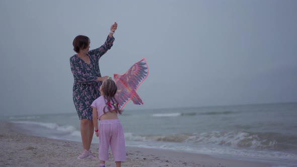 Mother with Little Daughter Playing Kite On Sea Beach