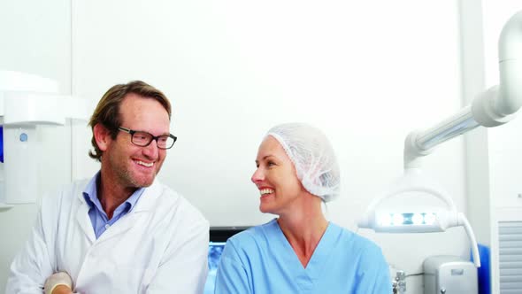 Smiling dentist and dental assistant standing with arms crossed