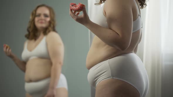Overweight Young Woman Stress Eating in Front of Mirror, Hating Her Fat Body