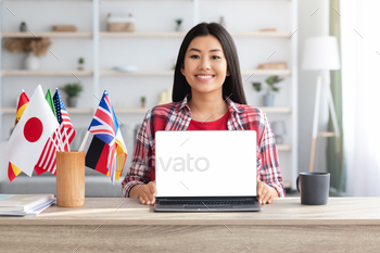 rating Laptop With Blank White Screen, Sitting At Desk With International Flags At Home, Korean Female Advertising Website For Distance Learning