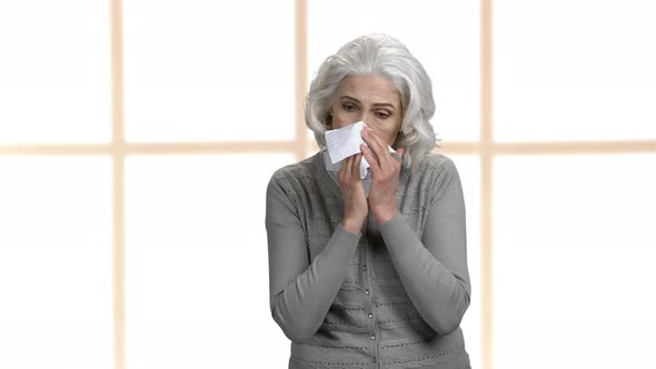 Sick Mature Woman Sneezing in Tissue