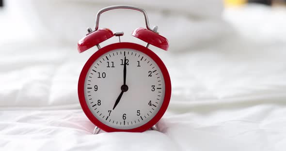 Red Alarm Clock for Seven in Morning is on Bed in Bedroom