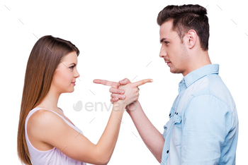  couple pointing each other while standing against white background