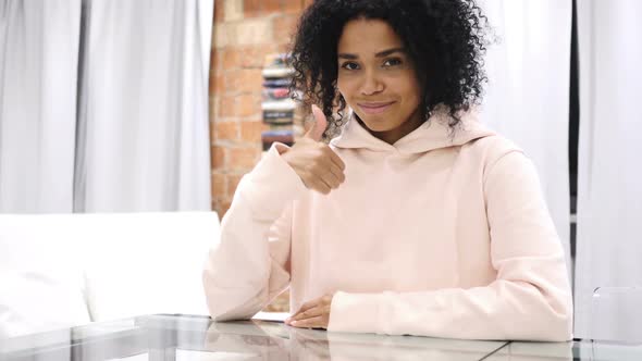 Upset AfroAmerican Woman Gesturing Thumbs Up Sitting in Loft Space