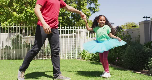 Happy biracial father and daughter dancing in garden together