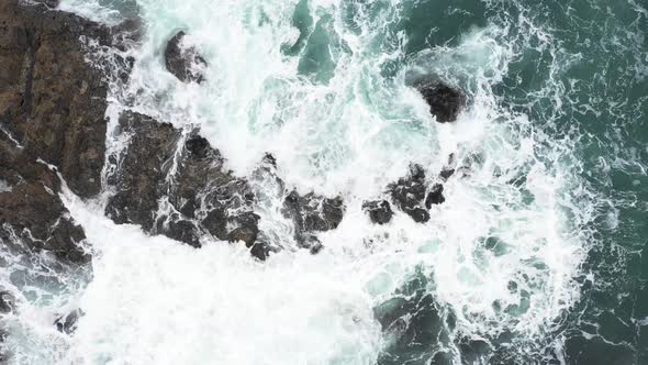 Aerial top view of rocks in the sea - Aerial video of majestic waves splashin