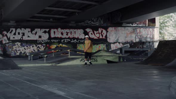 Young Skater Riding on Skate Board at Skate Park with Graffiti Wall Background