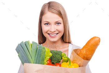 shopping bag full of groceries and looking at camera while standing against white background