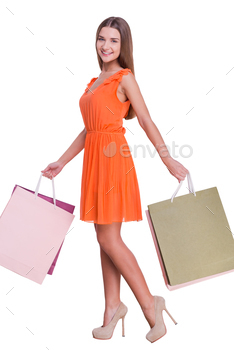  woman carrying shopping bags and smiling while standing against white background