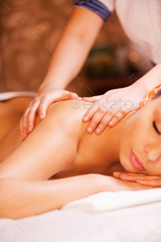  woman lying on front and keeping eyes closed while massage therapist massaging her back
