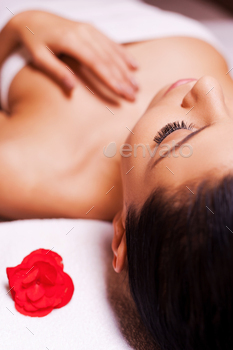  woman wrapped in towel lying on massage table and keeping eyes close