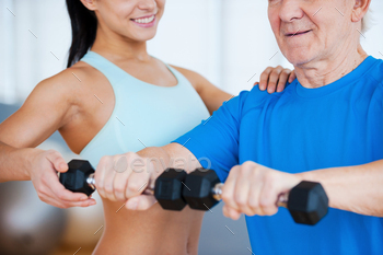 ale physical therapist helping senior man with fitness in health club