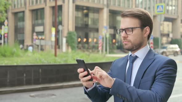 Businessman using Smartphone while Walking in Street