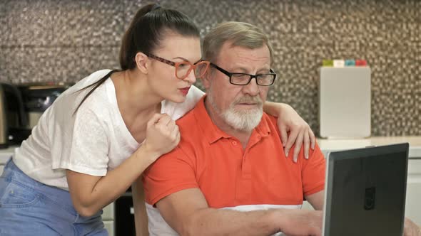 Adorable Brunette and Her Father Stare Intently at the Laptop Screen