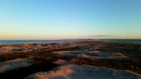 Aerial flyover sun lighting landscape with Pacific Ocean and colorful sky after sunset in background