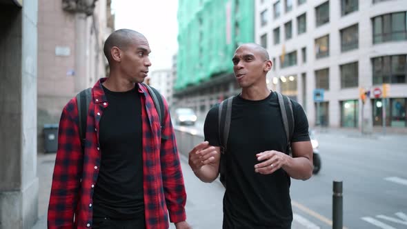 Two positive bald African brothers talking and walking on the street