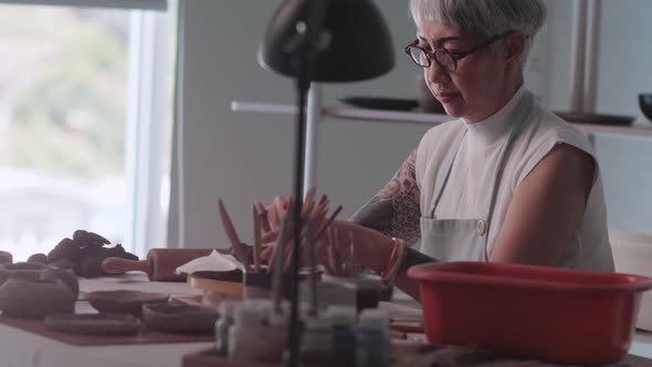 Asian elderly woman enjoying pottery work at home.