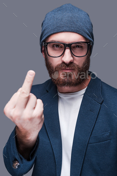g hand with middle finger outstretched looking at camera while standing against grey background