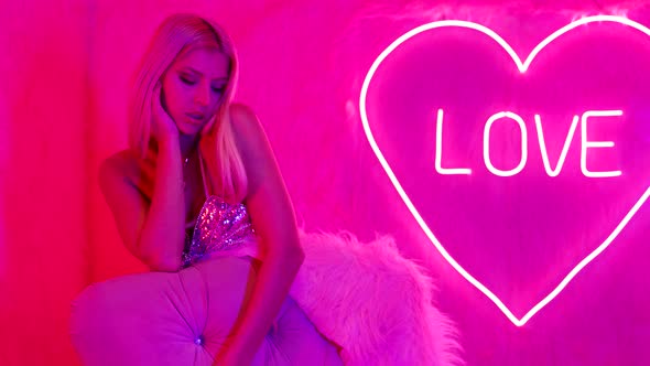Alluring Lady Against Pink Wall with Neon Heart and Inscription Love Bordello or Strip Club