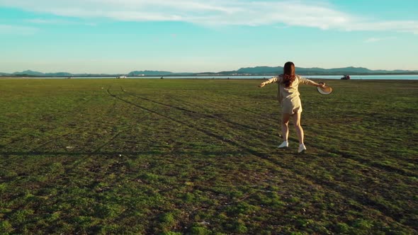 slow-motion of cheerful woman running across the green field with sunlight