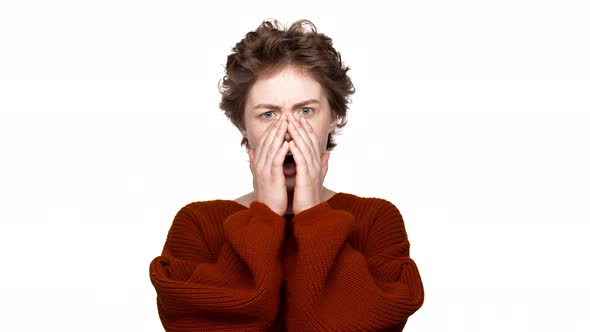 Indoor Portrait of Pretty Lady with Brown Curly Hair Being Shocked and Raising Hands at Open Mouth