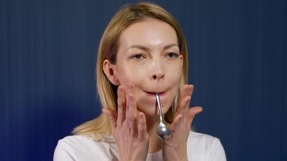 Woman Is Performing Exercises with Spoon for Tensing and Training Muscles of Face