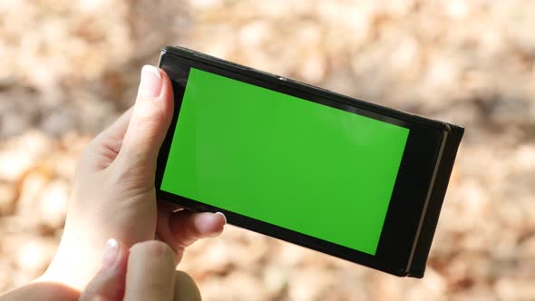 Outdoor shallow DOF with woman holding green screen display phone 4K 2160p 30fps UHD video - Female 